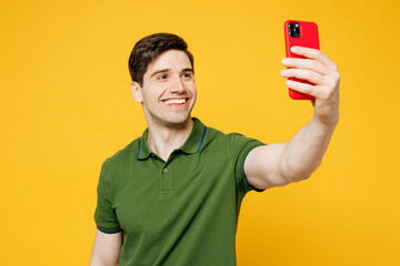 Wall Mural - Young caucasian happy man wears green t-shirt casual clothes oing selfie shot on mobile cell phone post photo on social network isolated on plain yellow background studio portrait. Lifestyle concept.