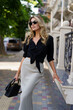 © Svetlana Sokolova - Elegant blond woman with wavy beautiful hairs  in stylish casual outfit  posing on the street. Fashion trendy accessories, silk scirt , black blouse.