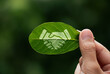 © Kannapat - Hand of human is holding painted green leaf with handshake icon, environment social and governance or ESG