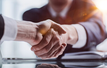 Wall Mural - Close-up high-angle view of unrecognizable business men handshaking after close deal and signed agreement at office over table paper contract.