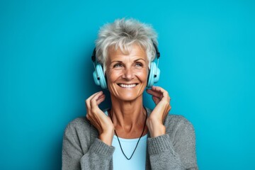 Headshot portrait photography of a grinning mature woman covering his ears against a turquoise blue background. With generative AI technology