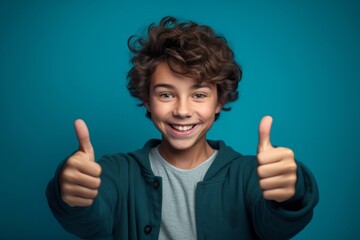 Wall Mural - Close-up portrait photography of a joyful boy in his 20s raising both thumbs up against a turquoise blue background. With generative AI technology