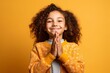 © Markus Schröder - Close-up portrait photography of a satisfied kid female joining palms in a gesture of gratitude against a bright yellow background. With generative AI technology