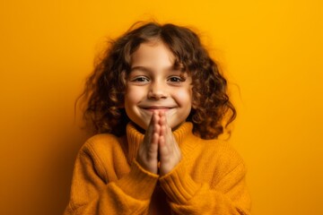 Canvas Print - Close-up portrait photography of a satisfied kid female joining palms in a gesture of gratitude against a bright yellow background. With generative AI technology