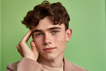 Wall Mural - Close-up portrait photography of a glad boy in his 20s making a i'm listening gesture with the hand on the ear against a pastel green background. With generative AI technology