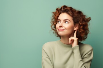 Wall Mural - Medium shot portrait photography of a glad girl in her 20s putting the hand on the chin as if thinking against a pastel green background. With generative AI technology