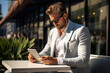© Sergio - Concentrated handsome male businessman in suit using tablet while sitting in outdoor cafe looking into gadget