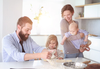 Young parents playing with children in the kitchen