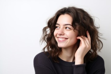 Wall Mural - Lifestyle portrait photography of a grinning girl in her 20s making a gesture of i'm thinking with the finger on the head against a pearl white background. With generative AI technology