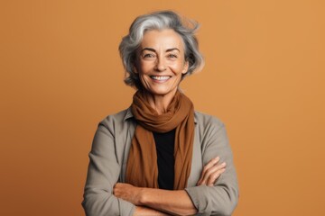 Poster - Medium shot portrait photography of a happy mature woman crossing the arms against a beige background. With generative AI technology