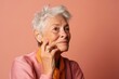 © Markus Schröder - Lifestyle portrait photography of a satisfied old woman putting the hand on the chin as if thinking against a beige background. With generative AI technology