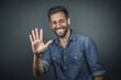 © Markus Schröder - Lifestyle portrait photography of a grinning boy in his 30s making a no or stop gesture with the extended palm against a cool gray background. With generative AI technology