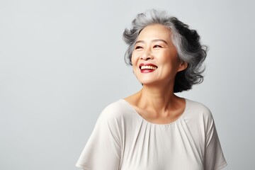 Portrait of a stylish beautiful Asian woman in her 50s. Skin care concept. Luxurious middle-aged woman with a short gray hair looking at copy space.