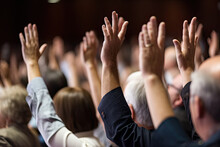 At A Professional Business Seminar, A Diverse Audience Raises Their Hands In An Important Decision.
