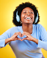 Poster - Portrait, heart hands and headphones of woman in studio for sign, kindness or thank you on yellow background. Happy african model, finger shape or icon of hope, love or emoji while listening to music