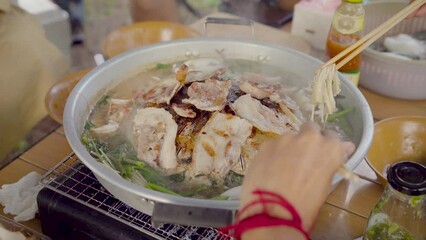 Wall Mural - Korean BBQ with sliced pork and vegetable soup, People hand using chopsticks grilled dinner the family. picnic outdoor