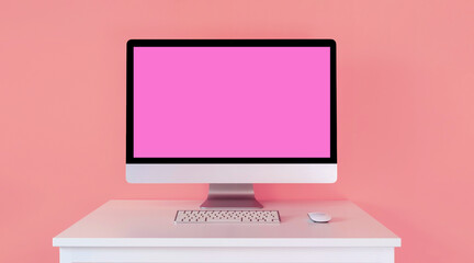 Big monitor with a pink screen, with a keyboard on a table, on a light pink background. Computer for work as a designer or freelance internet marketer. Layout of online courses for women.