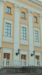 Wall Mural - Vertical tilt down establishing shot of part of white and yellow building with three wooden doorsVertical tilt down establishing shot of part of white and yellow building with three wooden doorsVertic