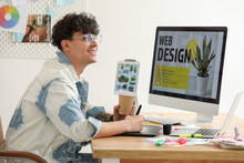 Male Graphic Designer With Cup Of Coffee Working At Table In Office