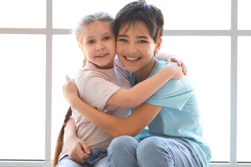 Poster - Little boy with his sister hugging near window