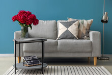 Vase Of Red Peonies With Coffee Table, Couch And Floor Lamp Near Blue Wall