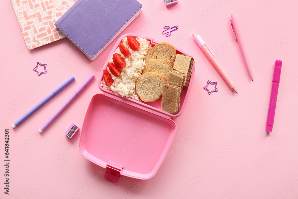 Lunchbox with delicious food and different stationery on pink background