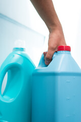 Wall Mural - Hand taking blue liquid soap bottle on blue background