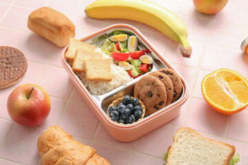 Lunchbox with different delicious food on pink tile background