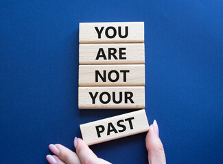 You are not your past symbol. Wooden blocks with words You are not your past. Beautiful deep blue background. Businessman hand. Business and You are not your past. Copy space.