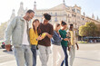 © CarlosBarquero - Group of smiling multiracial young people using cell phones. Cheerful students strolling around looking at technological devices. Happy fellow university students on study trip in European city.