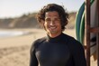 © Justlight - An Hispanic male surfer with arms crossed wearing wetsuit standing still against a blurred beach playing environment.