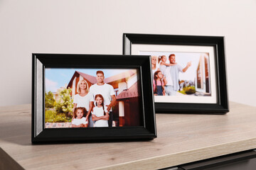 Wall Mural - Frames with family photos on wooden table near white wall