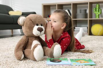 Wall Mural - Cute little girl playing with teddy bear at home