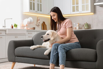 Wall Mural - Happy woman with cute Labrador Retriever dog on sofa at home. Adorable pet