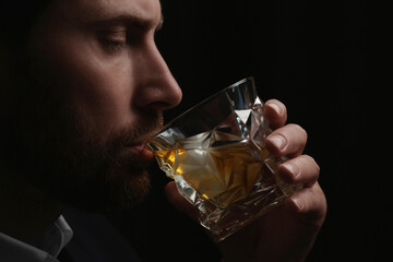 Wall Mural - Man drinking whiskey on black background, closeup