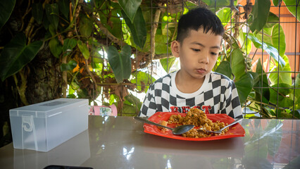 a little boy is eating fried rice