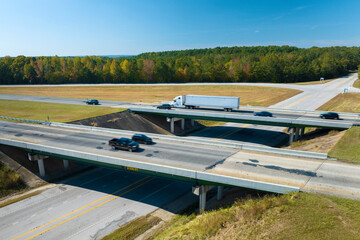 Canvas Print - View from above of busy american highway with fast moving traffic between woods. Interstate transportation concept