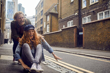 Young Couple Having Fun With A Skateboard On A City Street In London