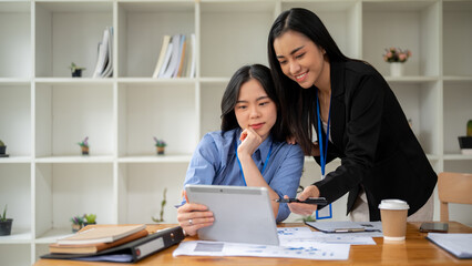 Wall Mural - Two professional Asian businesswomen are discussing work. Teamwork concept