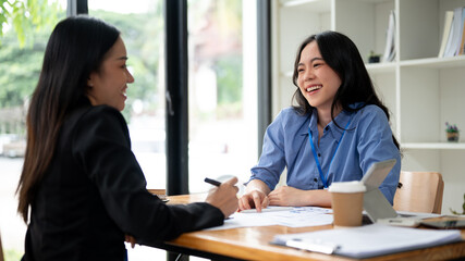 Wall Mural - An attractive Asian businesswoman or female financial consultant enjoys talking with her client