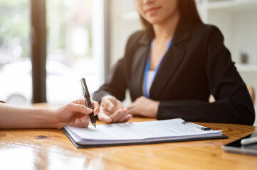 Wall Mural - A client signing a contract agreement or filling out a form in front of a businesswoman