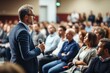 © amnaj - Male speaker holding a microphone conveying knowledge to the audience in the auditorium. Man presenter speaks to audience at seminar in the conference hall.