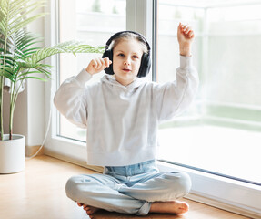 Wall Mural - Cute little girl listening to music in headphones