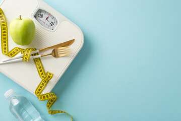 Wall Mural - Fitness and Sculpting in Style Theme. Overhead shot of weight scale, measuring tape, fresh green apple, water bottle, plus fork and knife on pastel blue backdrop. Ample room for text or promotion