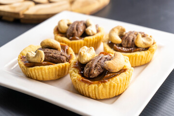 Wall Mural - tartlet with caramel and nuts on a white plate. pecan. cashew.food concept. dessert. bakery. diet