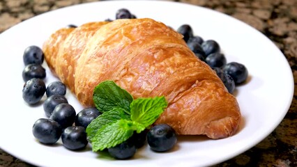 Wall Mural - Croissant with berries and mint on a plate, delicious breakfast. The camera moves along, close-up . High quality 4k footage