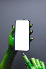 Poster - Vertical image of green monster hand holding smartphone with copy space on grey background