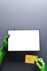 Poster - Vertical image of green monster hands with credit card and tablet with copy space on grey background