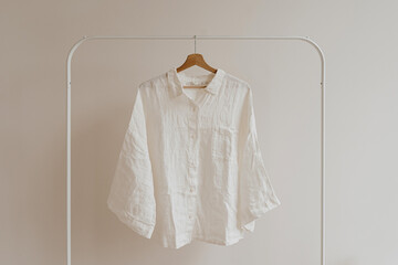 Wall Mural - White crumpled shirt, blouse on hanger over white wall. Aesthetic female fashion clothes, wardrobe concept