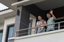 Happy Family (father, Mother And Infant Baby) Greeting Neighbors At Balcony Of House